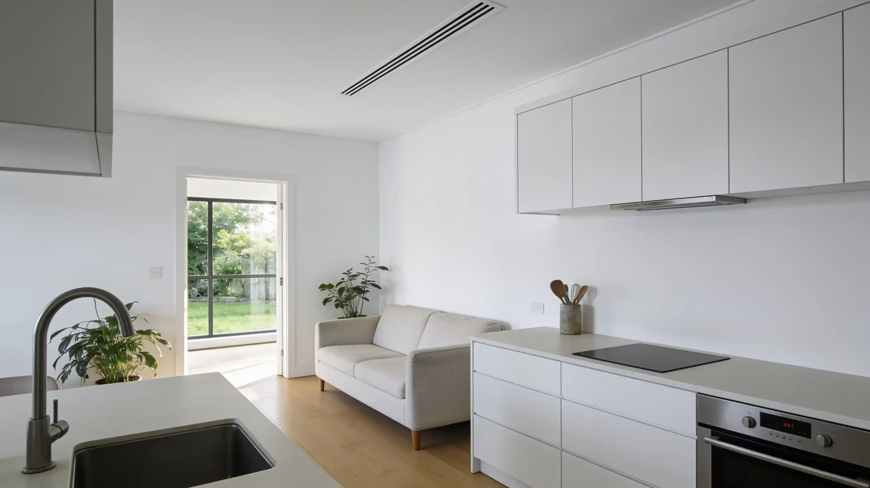 The same kitchen and living room with the wall unit gone and a slim white linear vent in the ceiling